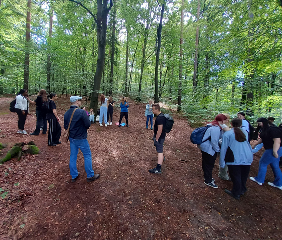 Gruppenfoto der Schüler*innen mit Lehrperson im kühlen Wald